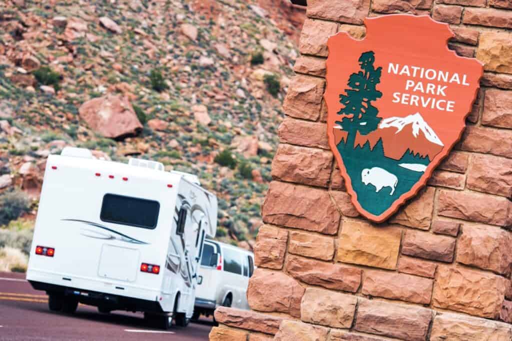 A van towing a trailer near a National Park Service sign. Photo: Shutterstock.
